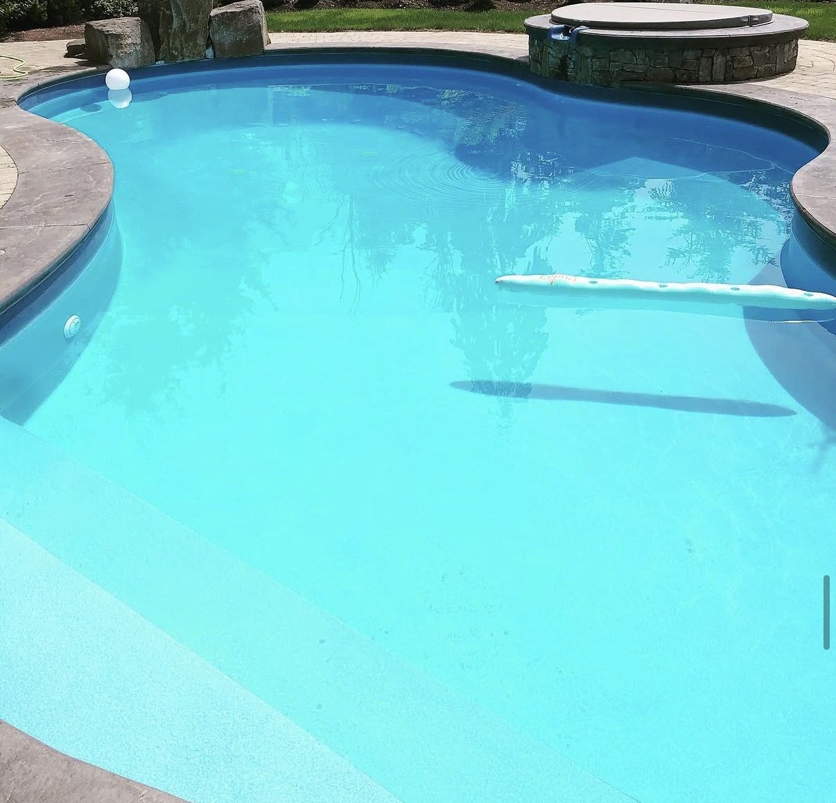 Freeform pool and stone hot tub with crystal clear turquoise water