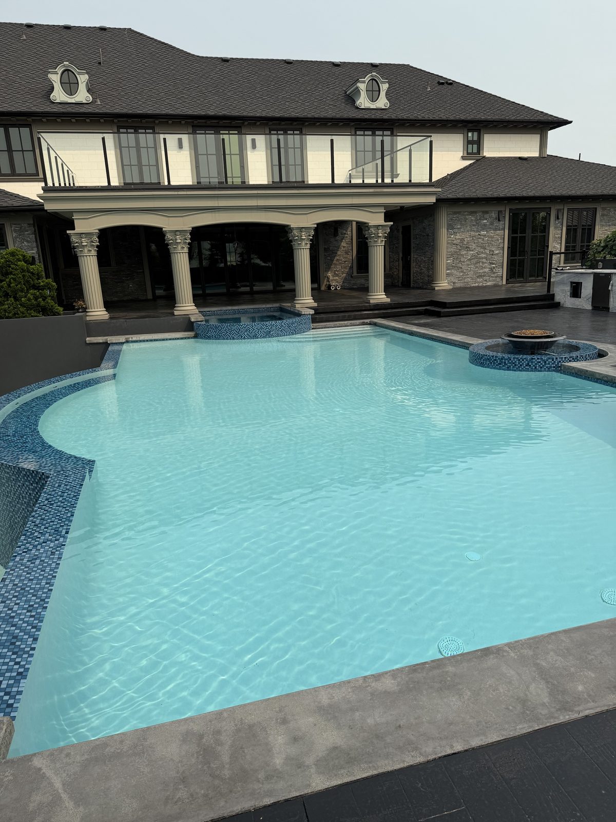 Mosaic tile pool with fire bowl feature and sun shelf