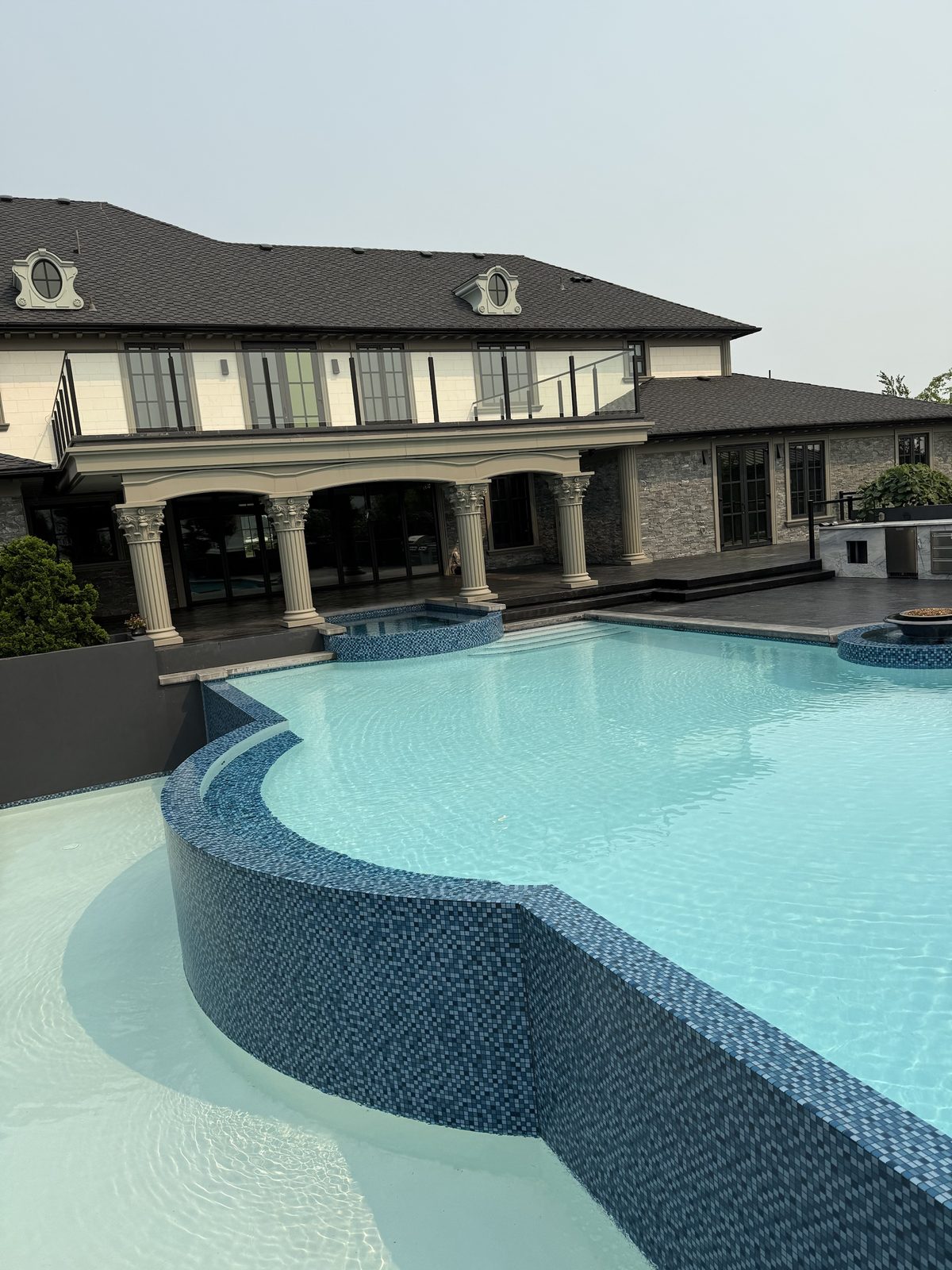 Glass mosaic tile pool and raised spa with clear turquoise water