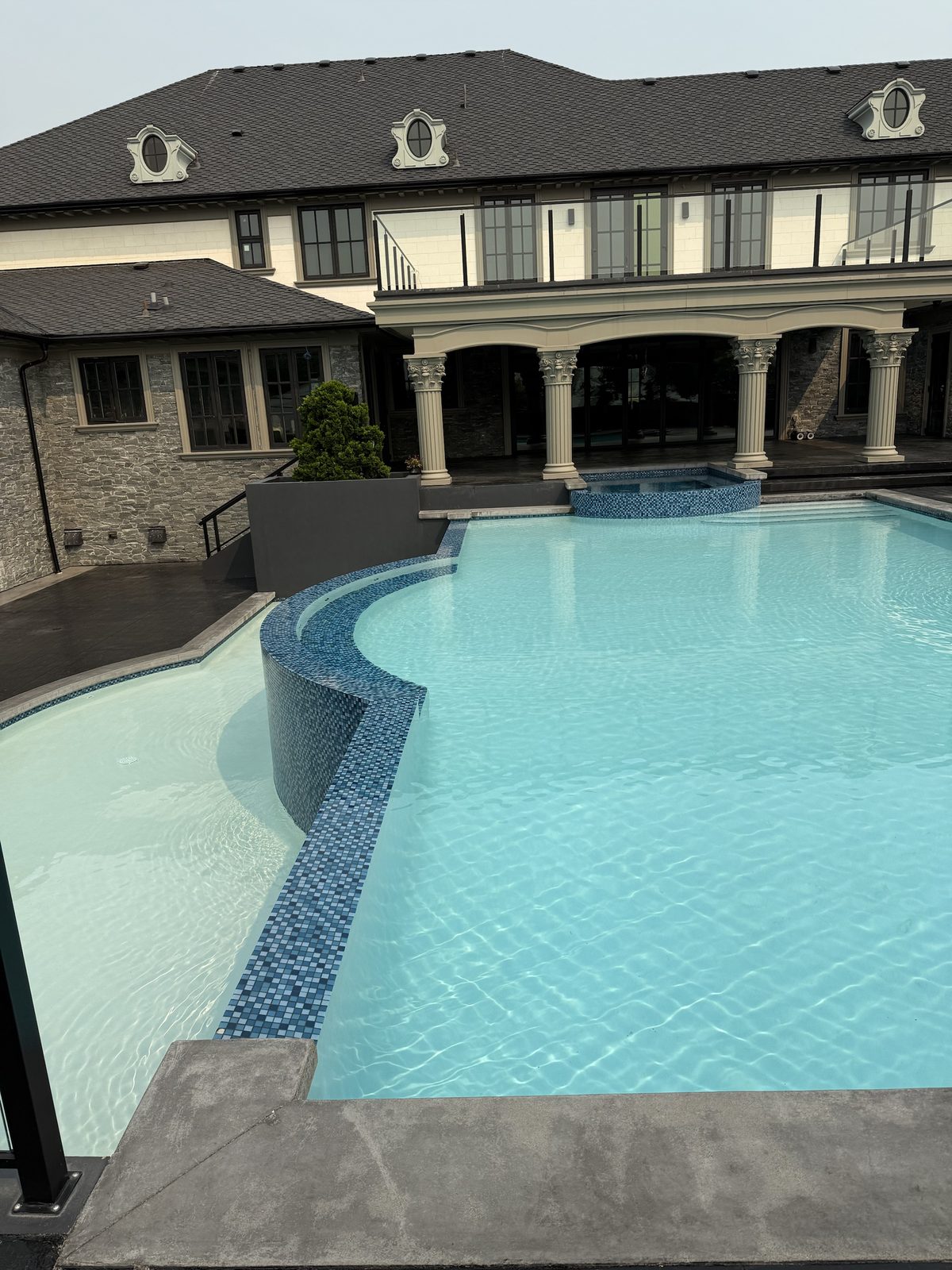 Wide view of a mosaic tile pool and sun shelf maintained by JK Pools and Spas