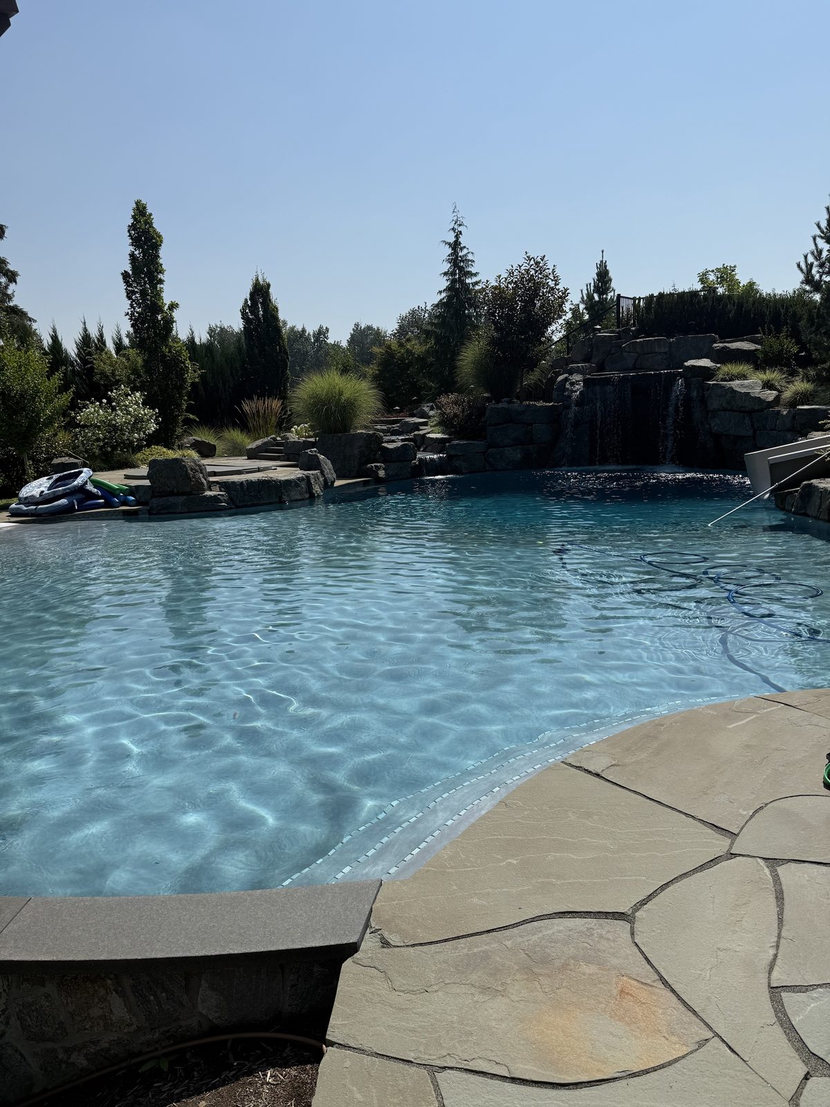 Rock waterfall pool with diving board and mature planting