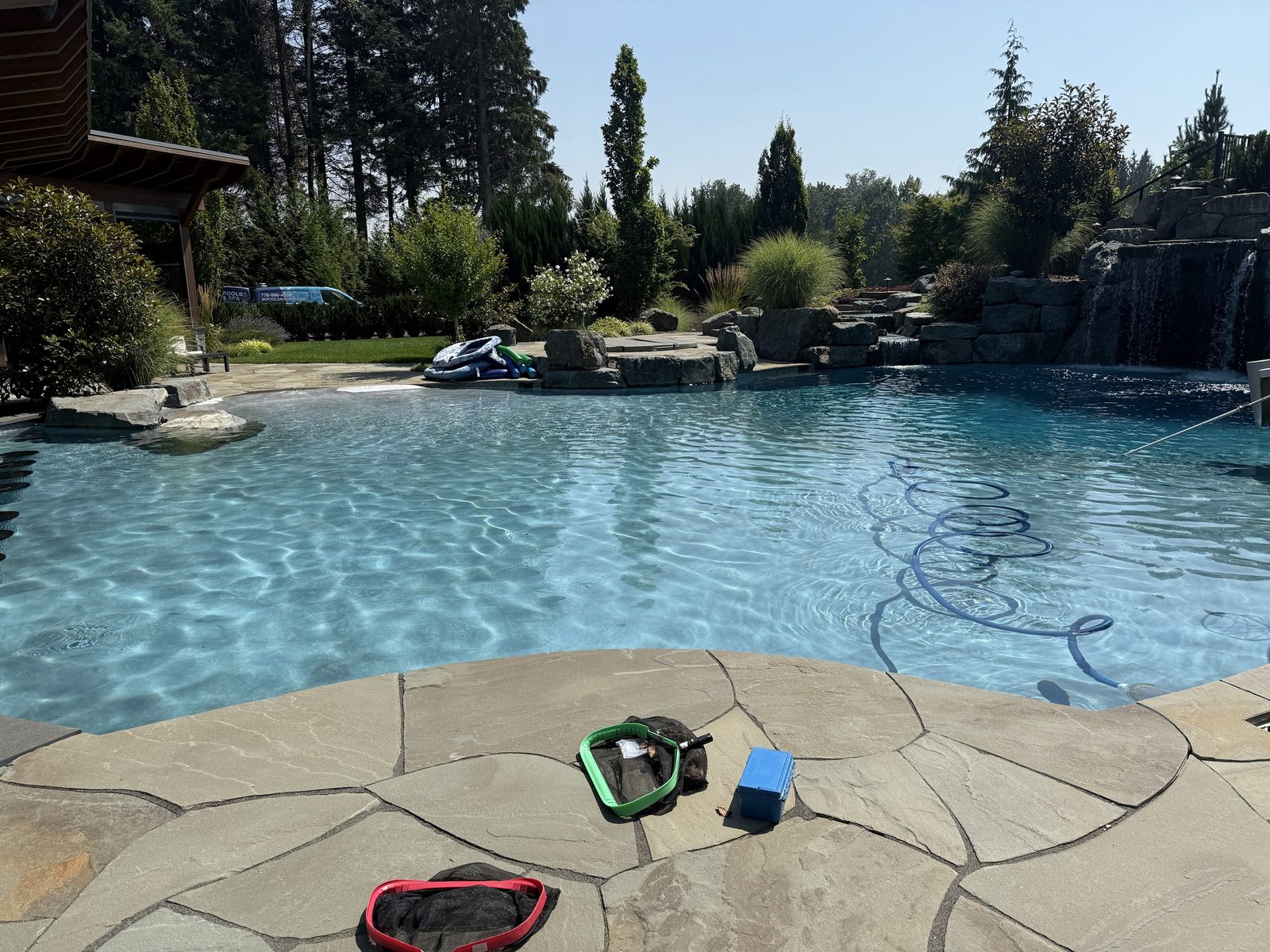 Skimmer nets and test kit on the pool deck during a service visit