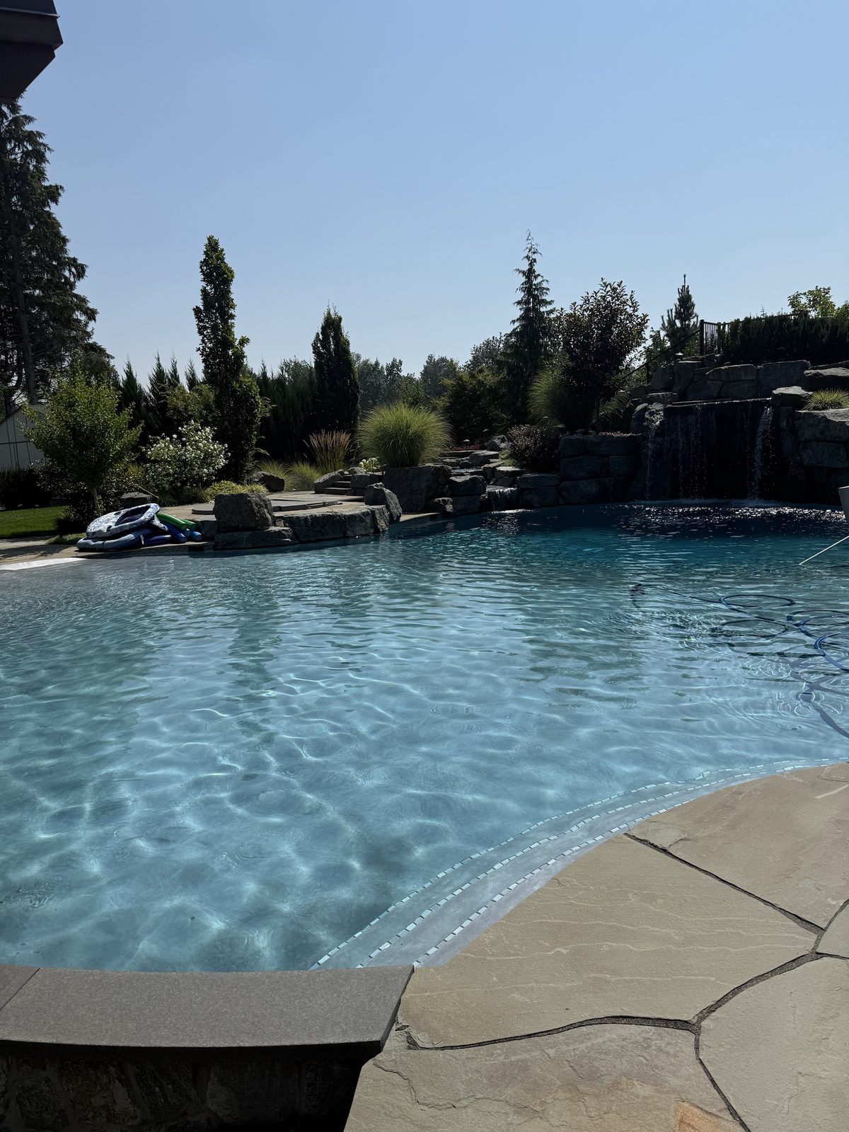 Rock waterfall pool with flagstone deck kept clear through the summer