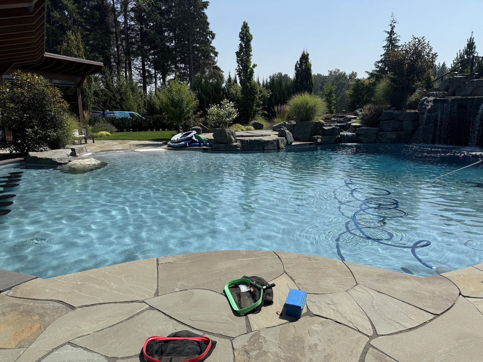 Rock waterfall pool with flagstone deck serviced by JK Pools and Spas in the Fraser Valley